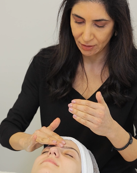 Medical aesthetician gently applying a soothing facial mask to a client's skin, as part of a comprehensive facial treatment.